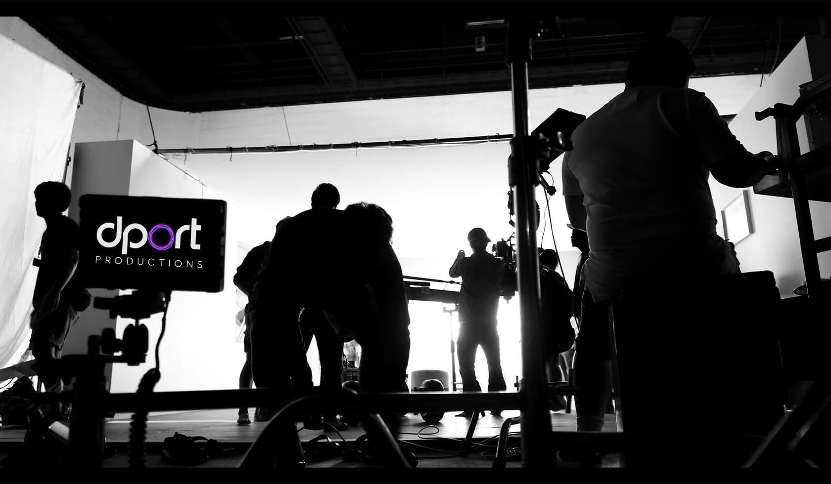 Film crew working on set with silhouettes and a monitor displaying the DPORT Productions logo