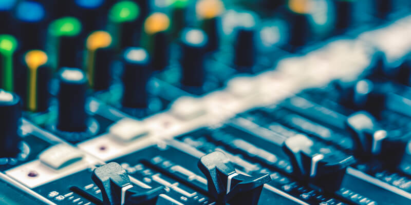 Close-up of an audio mixing console with faders and control knobs in a recording or production studio